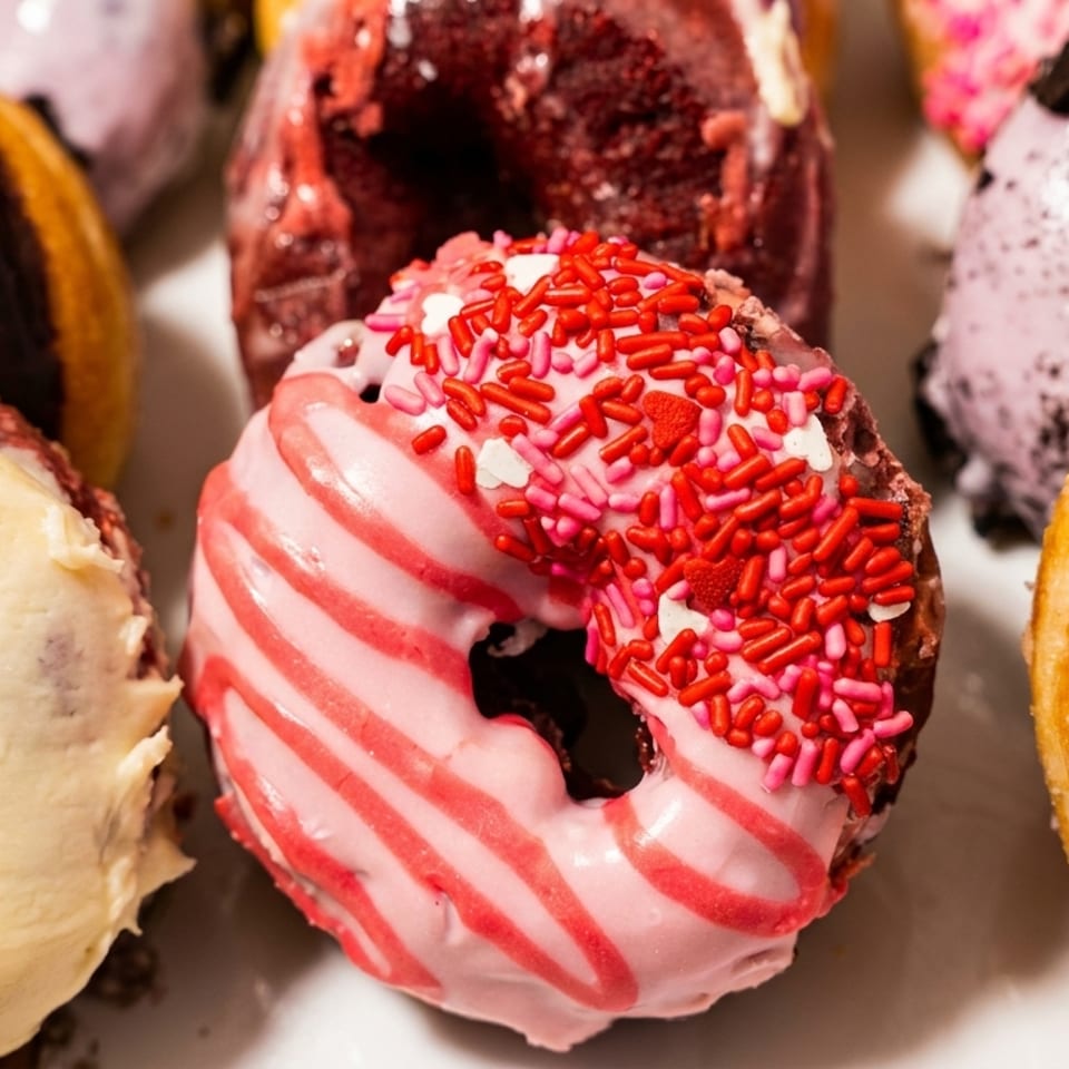 Close-up of assorted colorful donuts with various frostings and sprinkles, including pink, chocolate, and cereal.